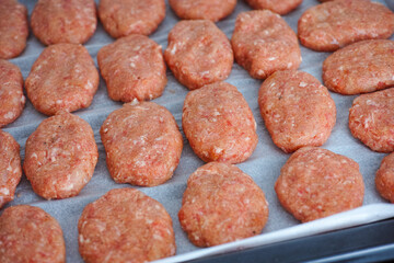 Raw beef patties on a baking tray