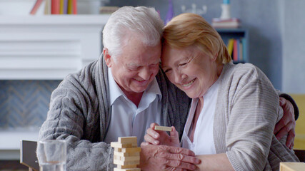 Happy elderly couple playing Board games in living room at home