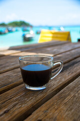 Black coffee on the wooden table, beachside, travel concept , nature light. Thailand