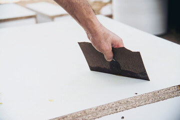 Carpenter making wooden built-in furniture putting rubber glue to attach laminate surface