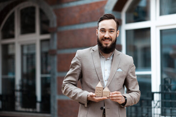 Real estate agent. Smiling man with miniature houses in his hands. Apartment rent, home insurance.