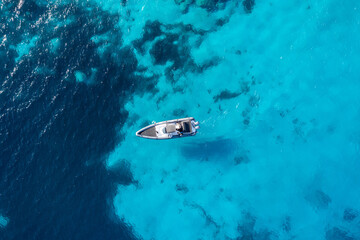Naklejka na ściany i meble Greece, Cyclades. Aerial drone view of a speed boat on turquoise color sea water