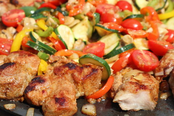 Grilling in a cast iron pan. Meat - pork neck with vegetables: onion, mushrooms, colorful peppers and zucchini
