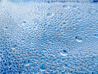 An abstraction. Drops of water, dew, on the blue glass.