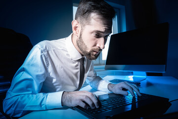 An office worker works overtime. Portrait of an office worker working at night. Close-up of man who...