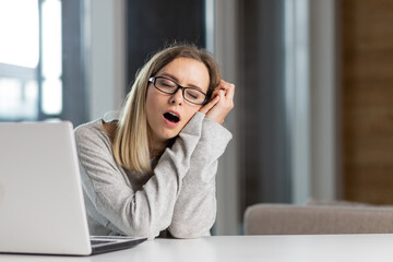 exhausted woman at work yawns from painful sensations caused by wrong posture, sedentary work, long sitting at a laptop fibromyalgia falls asleep at the computer