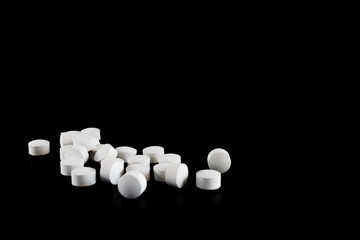 Small group of white pills isolated on black background