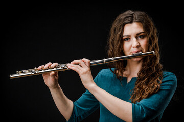 Portrait of a woman playing a transverse flute, isolated on a black background.