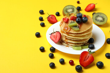 Concept of delicious dessert with pancakes on yellow background