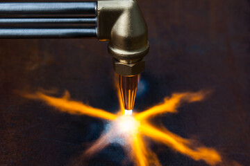 Gas cutting of metal. Gas cutter with copper nozzle with a stream of fire directed at the metal. Heating up the metal with a gas cutter.