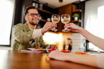 Photo of smiling guy, having romantic lunch, drinking a wine and toasts with his girl.