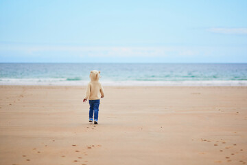 Adorable toddler girl on the sand beach at Atlantic coast of Brittany, France