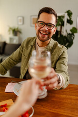 Photo of smiling guy, having romantic lunch, drinking a wine and toasts with his girl.
