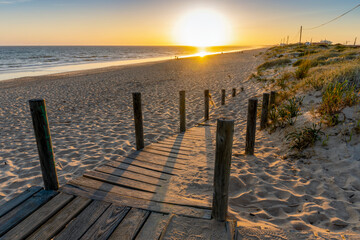 Fototapeta na wymiar Wide sandy Faro beach with dunes and walkways by the sunset, Algarve, Portugal