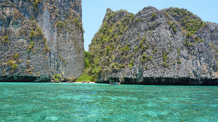 Blue water, green hills and steep rocks. The boat sails near the island. Boat with tourists in the...