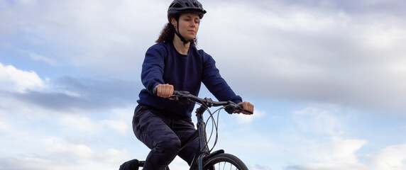 Adult Caucasian Woman Riding a Bicycle on a path by a lake in a modern city park. Spring Evening. Taken in Green Timbers Urban Forest, Surrey, Vancouver, British Columbia, Canada.