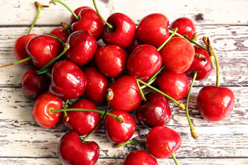 Ciliegie mature ammucchiate su un fondale di vecchio legno verniciato di bianco.