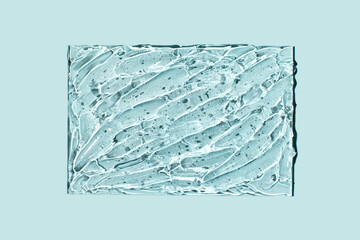 Transparent cosmetic gel in glass isolated on blue background. Make-up and cosmetics texture...