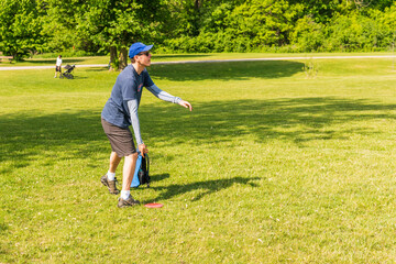 Disc golf is a flying disc sport in which players throw a disc at a target; it is played using rules similar to golf, this player is enjoying a early summer morning on a course in Toronto.