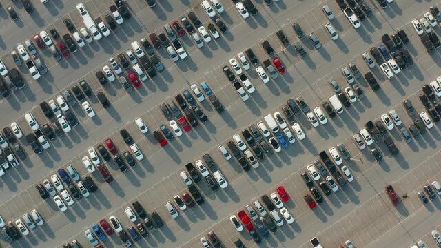 Aerial top down orbit of parking lot with new and used cars, trucks, SUVs. Vehicle auto industry in America, USA.