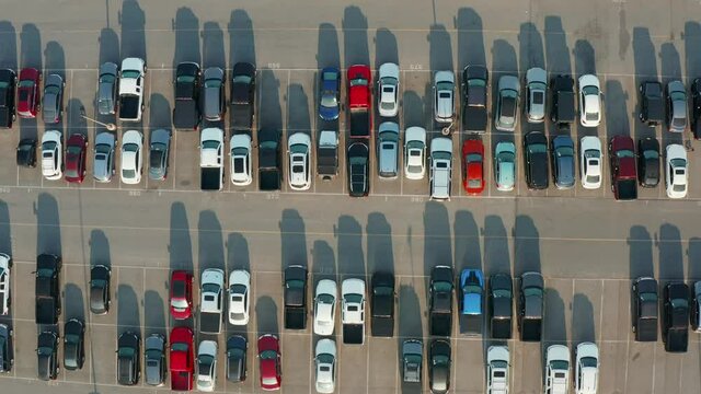 Rows of new and used cars at auto dealership parking lot. Many trucks, SUVs during magic hour. Shadows at magic hour. Aerial top down view.