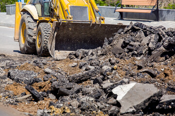 Fototapeta premium special road machinery a tractor with a bucket removes the remains of pieces of asphalt road surface repair work close-up nobody.