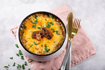 Julienne with potatoes and mushrooms in a baking dish on a light background. Traditional French dish