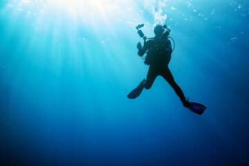 diver with equipment for underwater shooting underwater on a blue background 