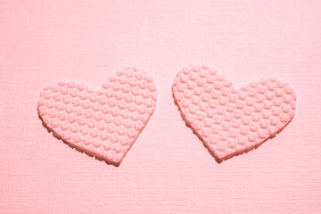 Two pink hearts made of textured material on the table