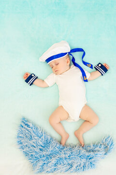 A Baby Boy On A Blue Background Sleeps In A Sailor Suit And Swims On The Waves In His Sleep