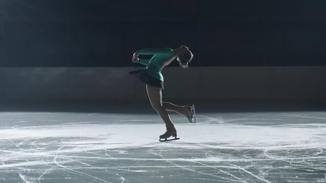 graceful girl performs a pirouette on skates, teenage figure skater perfects the execution of rotations while standing on skates in the evening, glides on the ice