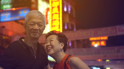 Obraz na płótnie Canvas Asian senior couple happy traveling in Bangkok China town at night colorful lifestyle and food