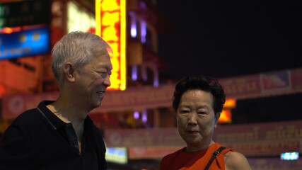 Asian senior couple happy traveling in Bangkok China town at night colorful lifestyle and food