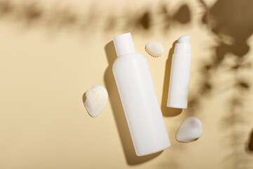 White cosmetic jar with seashells on a beige background with hard shadows. Beauty salon concept and summer tanning cosmetics