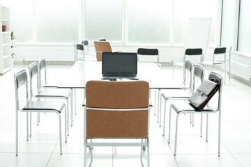 Flipchart laptop chairs glass table in a bright office space