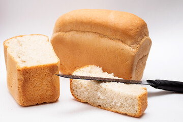 Whole grain loaf and Slices of fresh bread with knife for cut on white background