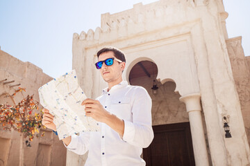 Handsome man in white shirt looking at map and looking for ways to discover new attractions in the...