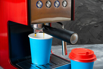 Red coffee machine fills a blue paper cup. Coffee to go.
