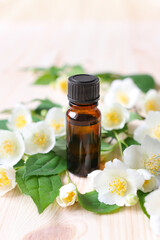Jasmine oil in a glass bottle on a wooden table. Jasmine flowers for relaxation and aromatherapy.