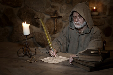 Old monk writes an old letter in the Middle Ages - obrazy, fototapety, plakaty