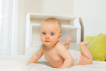 Baby girl standing on hands in bed look at camera