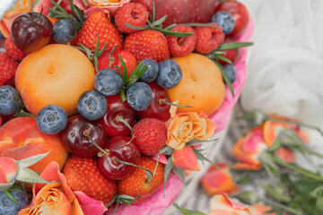 On a blanket a Basket with fruits, a bouquet of roses and a lady's summer hat.Natural background.There is a place for text