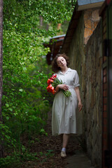 beautiful young girl walks in the garden with a bouquet of tulips, brunette in a body dress. Bouquet of tulips. Spring time.