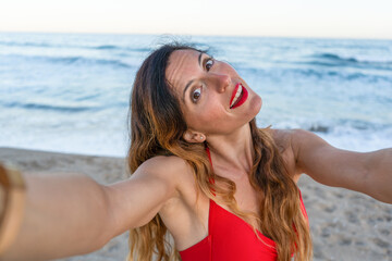 Naklejka premium Beautiful young woman having fun taking a selfie on beach at sunset.