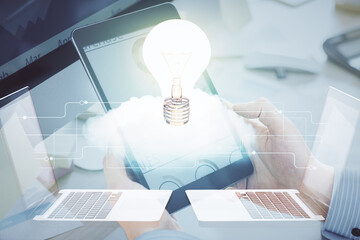 Double exposure of man's hands holding and using a digital device and bulb hologram drawing. Idea concept.
