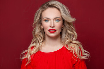 Smiling mature woman with blonde hair on red background