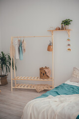 The concept of home comfort. In the center is a wooden clothes rack, a wooden shelf with toys, a bed and a large green flower.