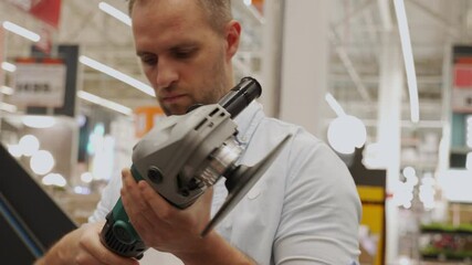 Adult man chooses a new angle grinder in a tool shop