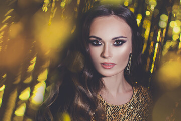 Cute young woman celebrity with makeup on golden bokeh background