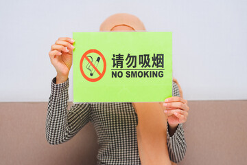 Fototapeta na wymiar person holding a box with a message, picture of woman with smoking restriction sign.